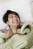woman laughing in bed
