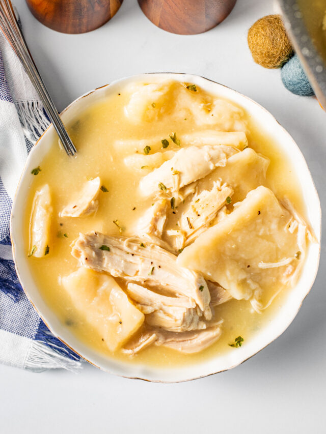 Golden chicken and dumplings in a white bowl